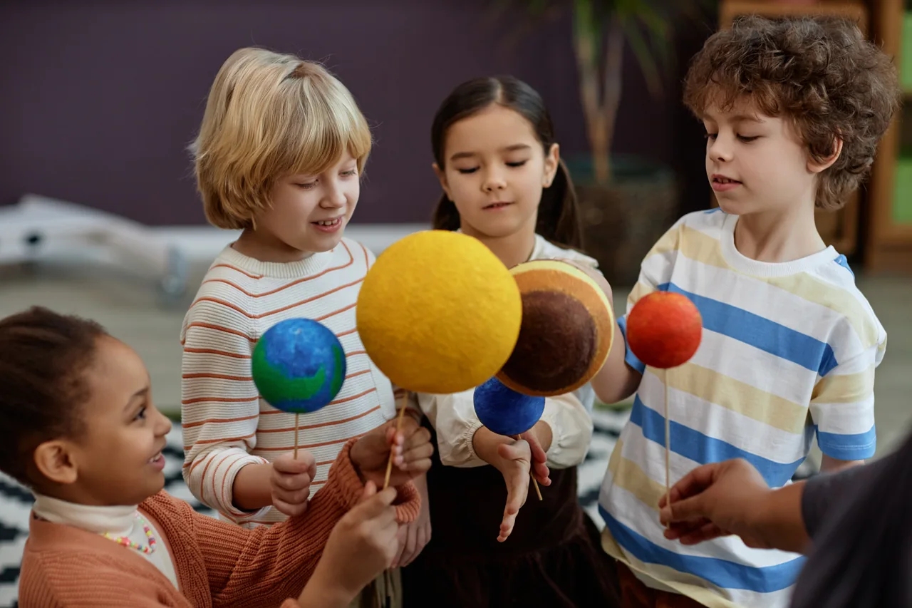 Children discovering a colourful model of the solar system together